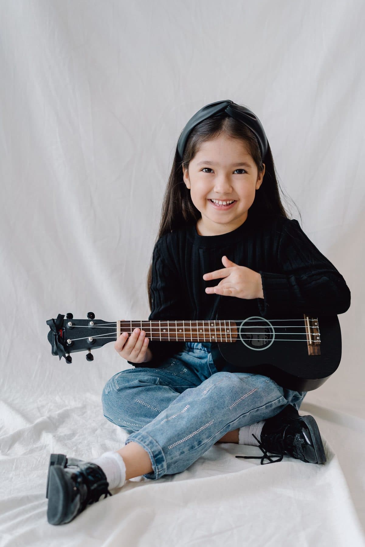 A child sitting and playing a ukulele.